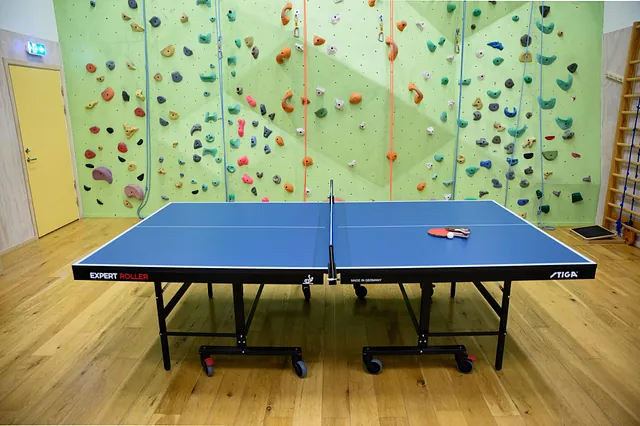Bordtennisbord foran klatrevegg med fargerike grep og tau