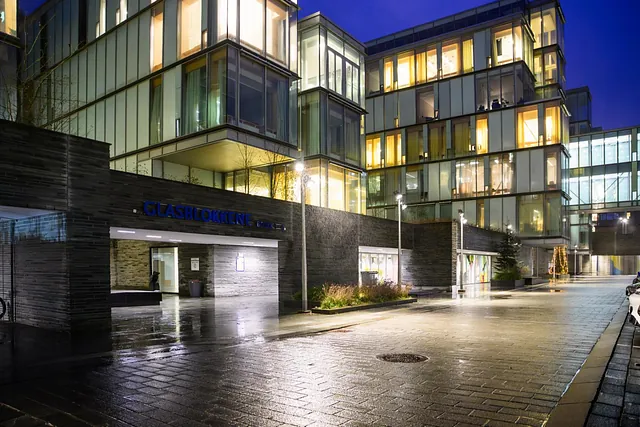 Moderne bygg med glassfasade og opplyste vinduer om kvelden